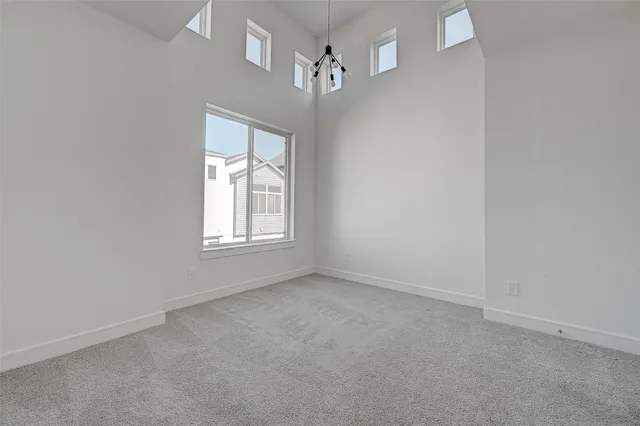 an empty room with windows and chandelier fan