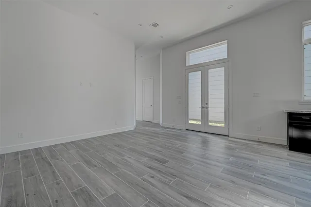 a view of an empty room with wooden floor and a fireplace