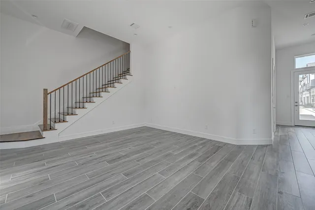 a view of an empty room with wooden floor and stairs