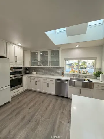 a large kitchen with cabinets a sink and wooden floor