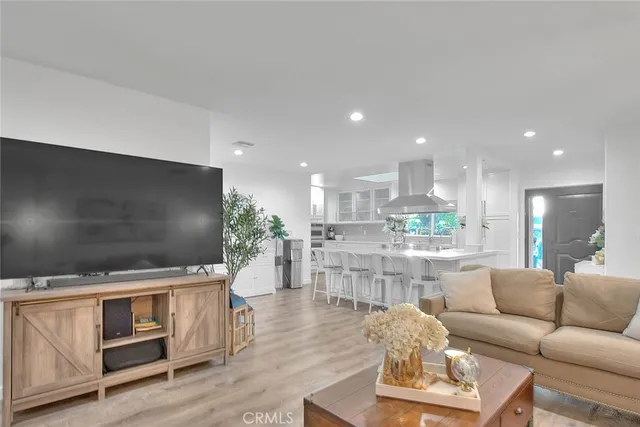 a living room with stainless steel appliances furniture and a flat screen tv
