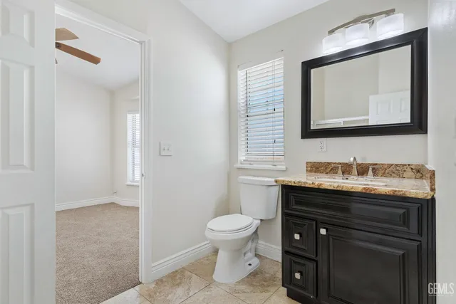 a bathroom with a granite countertop toilet sink and mirror