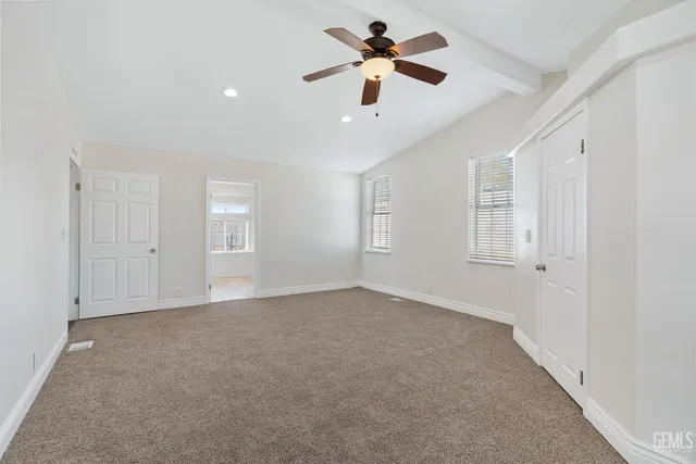 an empty room with chandelier fan and windows