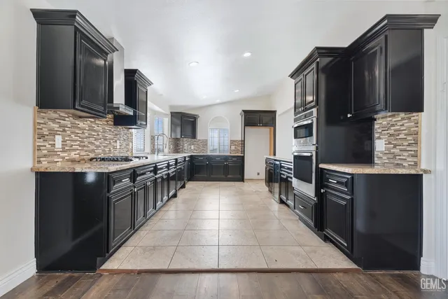 a kitchen with stainless steel appliances kitchen island granite countertop a stove refrigerator and cabinets