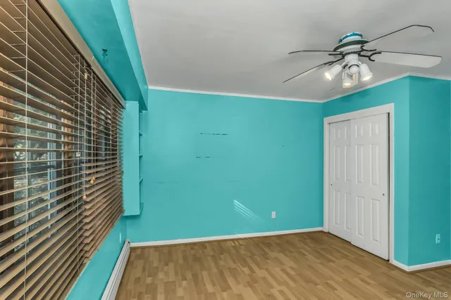 a view of an empty room with window and chandelier fan