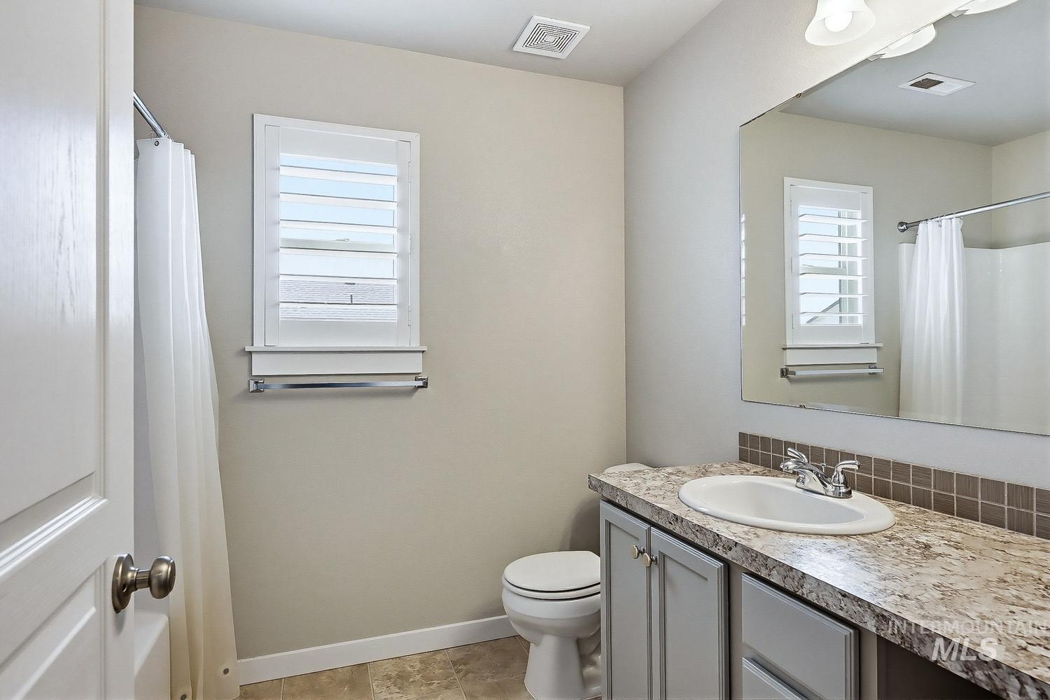 846 North Hidden View Way Star, ID 83669 - Photo 39 of 49 Bathroom featuring a vanity with an integrated sink, a rectangular mirror, and a window with white louvered shutters