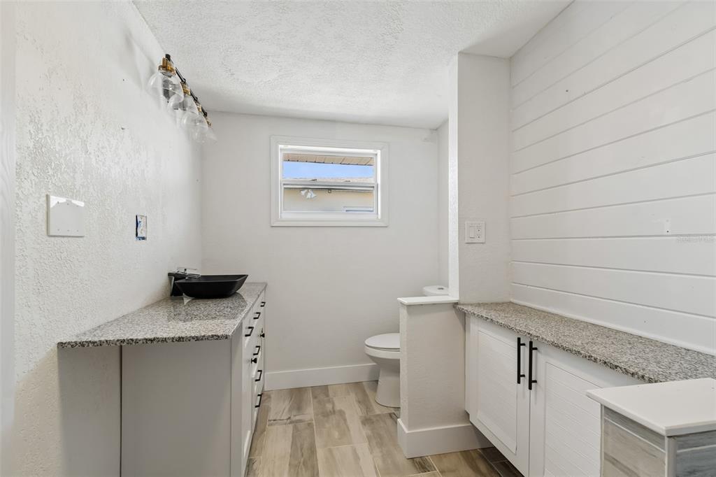 16108 5th Street East Redington Beach, FL 33708 - Photo 22 of 46 a bathroom with a granite countertop sink a toilet and a mirror