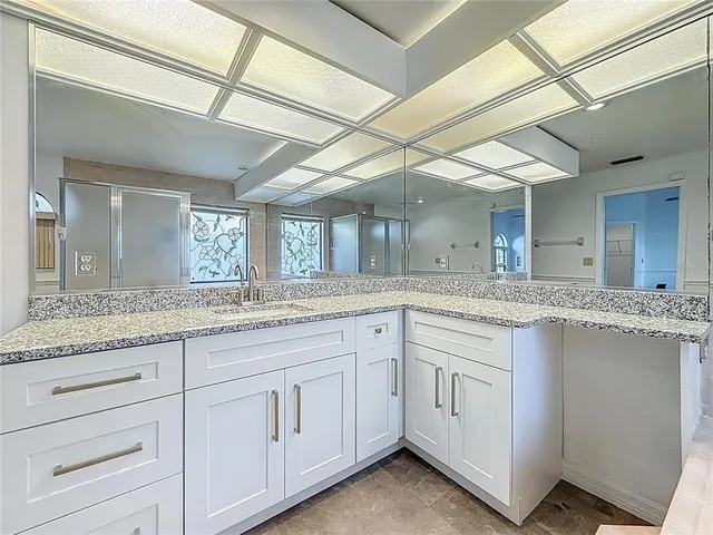 a bathroom with a granite countertop toilet a sink and a large mirror