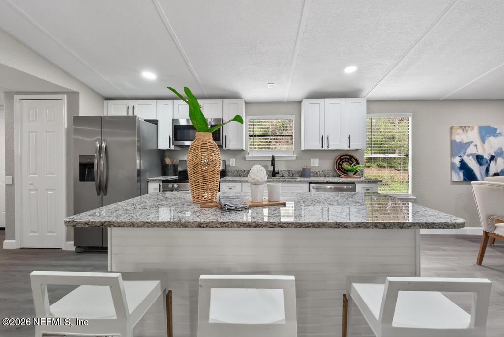 95422 Plum Loop Fernandina Beach, FL 32034 - Photo 36 of 84 a kitchen with stainless steel appliances granite countertop a table chairs sink and cabinets