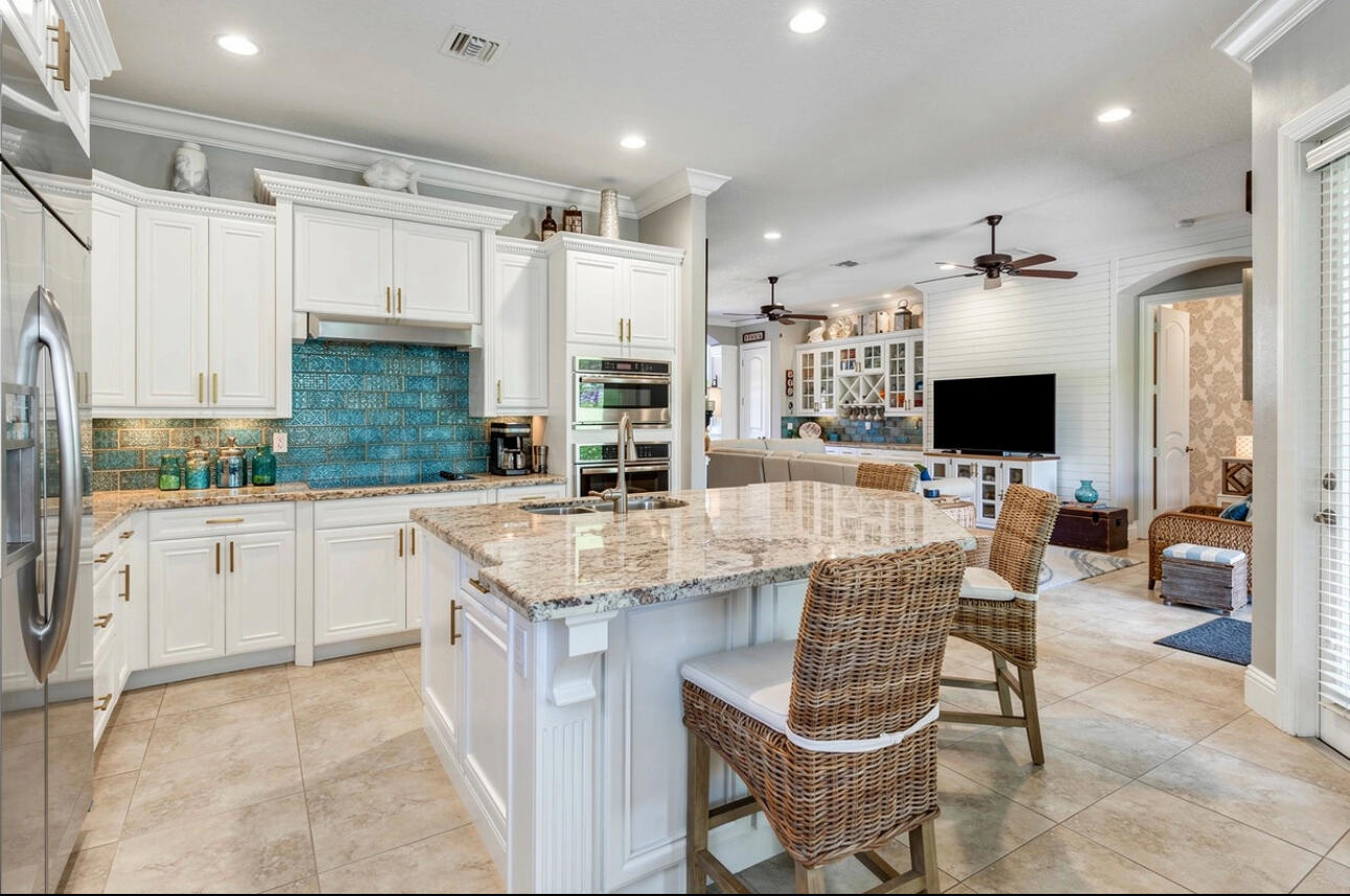 183 Calmo Circle Port St. Lucie, FL 34984 - Photo 12 of 38 a kitchen with stainless steel appliances kitchen island granite countertop a table chairs sink and cabinets