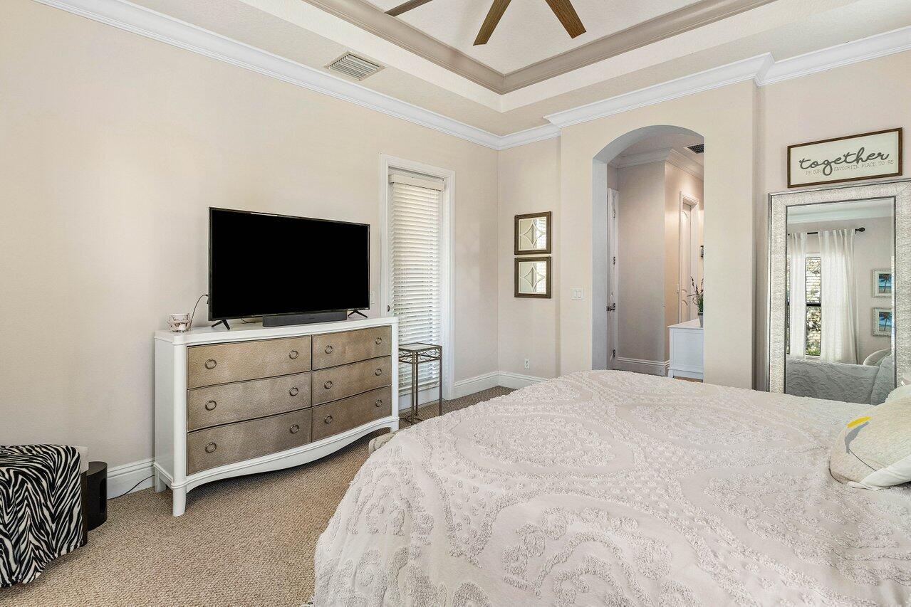 183 Calmo Circle Port St. Lucie, FL 34984 - Photo 18 of 38 a bedroom with a bed and a flat screen tv in white cabinets