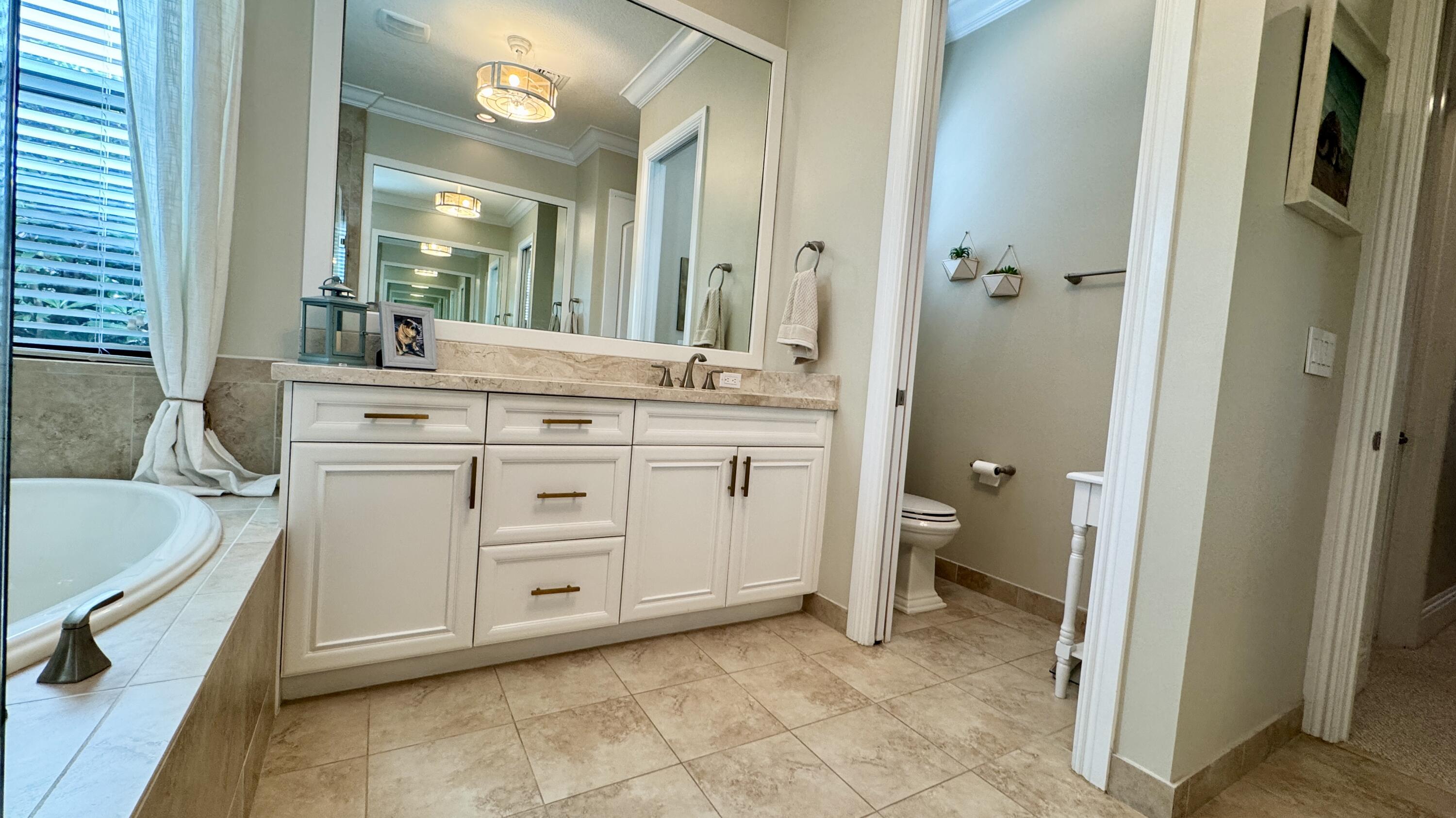 183 Calmo Circle Port St. Lucie, FL 34984 - Photo 22 of 38 a spacious bathroom with a double vanity sink a mirror and a bathtub