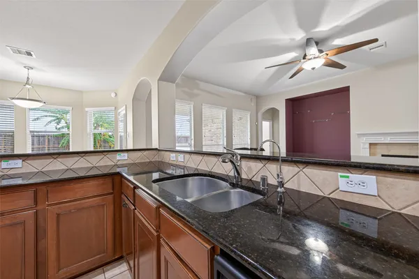 a kitchen with granite countertop a sink a counter top space cabinets and stainless steel appliances