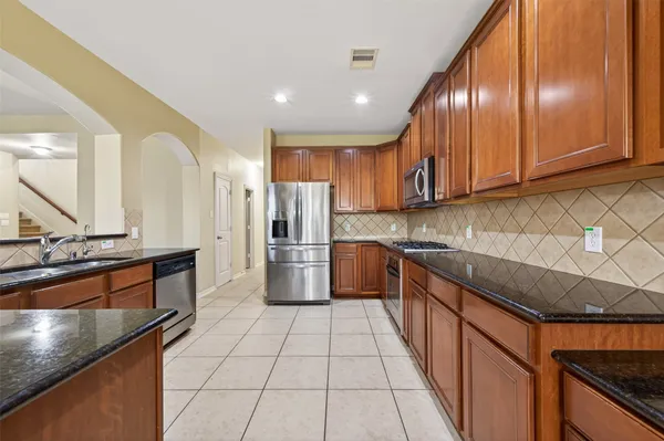 a kitchen with stainless steel appliances granite countertop a stove a sink and a microwave