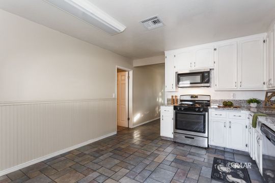 640 Sydnor Avenue Ridgecrest, CA 93555 - Photo 12 of 28 a kitchen with granite countertop a refrigerator stove and microwave