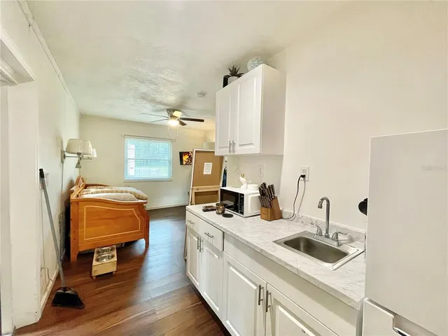 a kitchen that has a sink and a stove with wooden floors