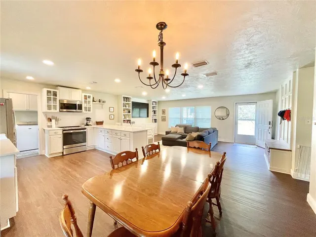 a dining room with wooden floor a chandelier a wooden table and chairs