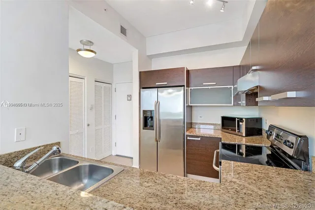 a kitchen with stainless steel appliances granite countertop a refrigerator and a sink