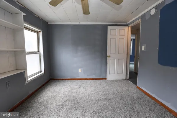 an empty room with windows and fan