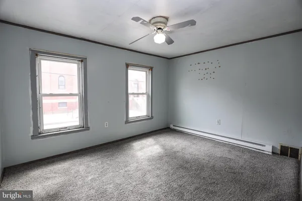 an empty room with windows and fan