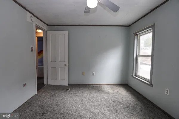a view of an empty room with window and chandelier fan