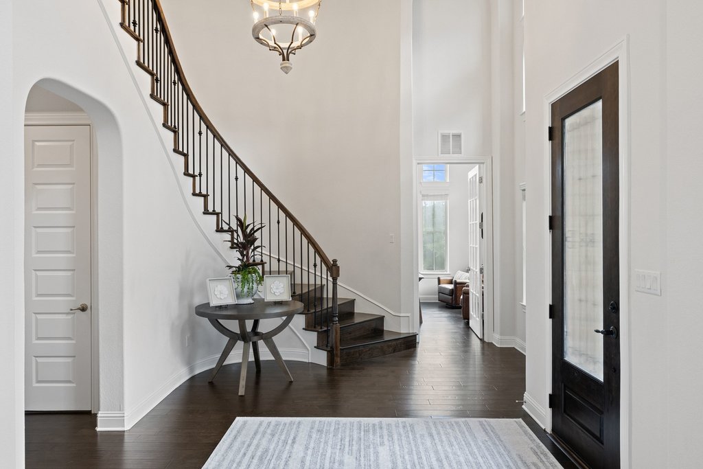 215 Lodestone Lane Austin, TX 78738 - Photo 3 of 40 A grand entrance welcomes guests with soaring ceilings, a sweeping staircase, and wood flooring.