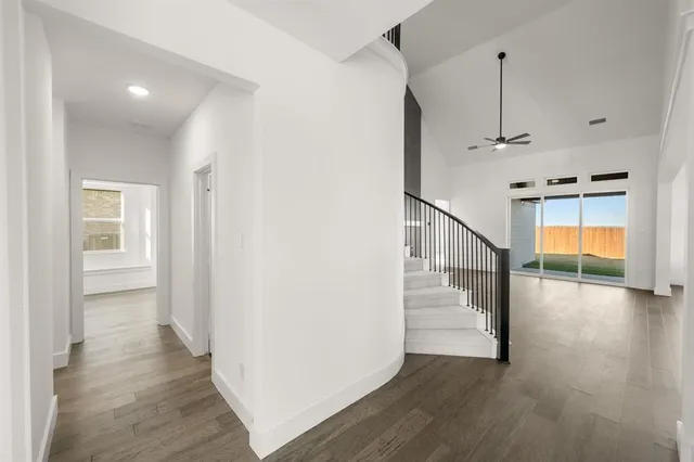 an empty room with wooden floor ceiling fan and windows