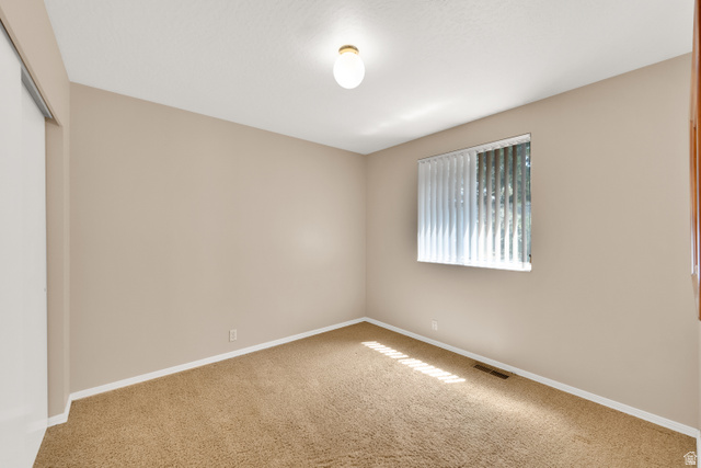 8029 Angel Street Sandy, UT 84070 - Photo 8 of 21 Carpeted room featuring a window with vertical blinds, a ceiling-mounted light fixture, and a white baseboard trim