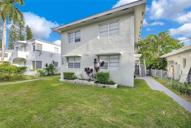 a view of a white house next to a yard