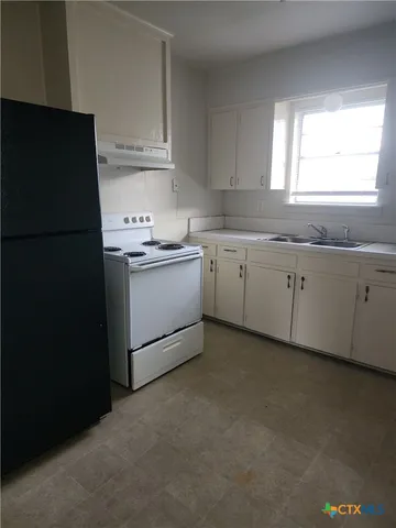 a kitchen with granite countertop cabinets appliances a sink and a window
