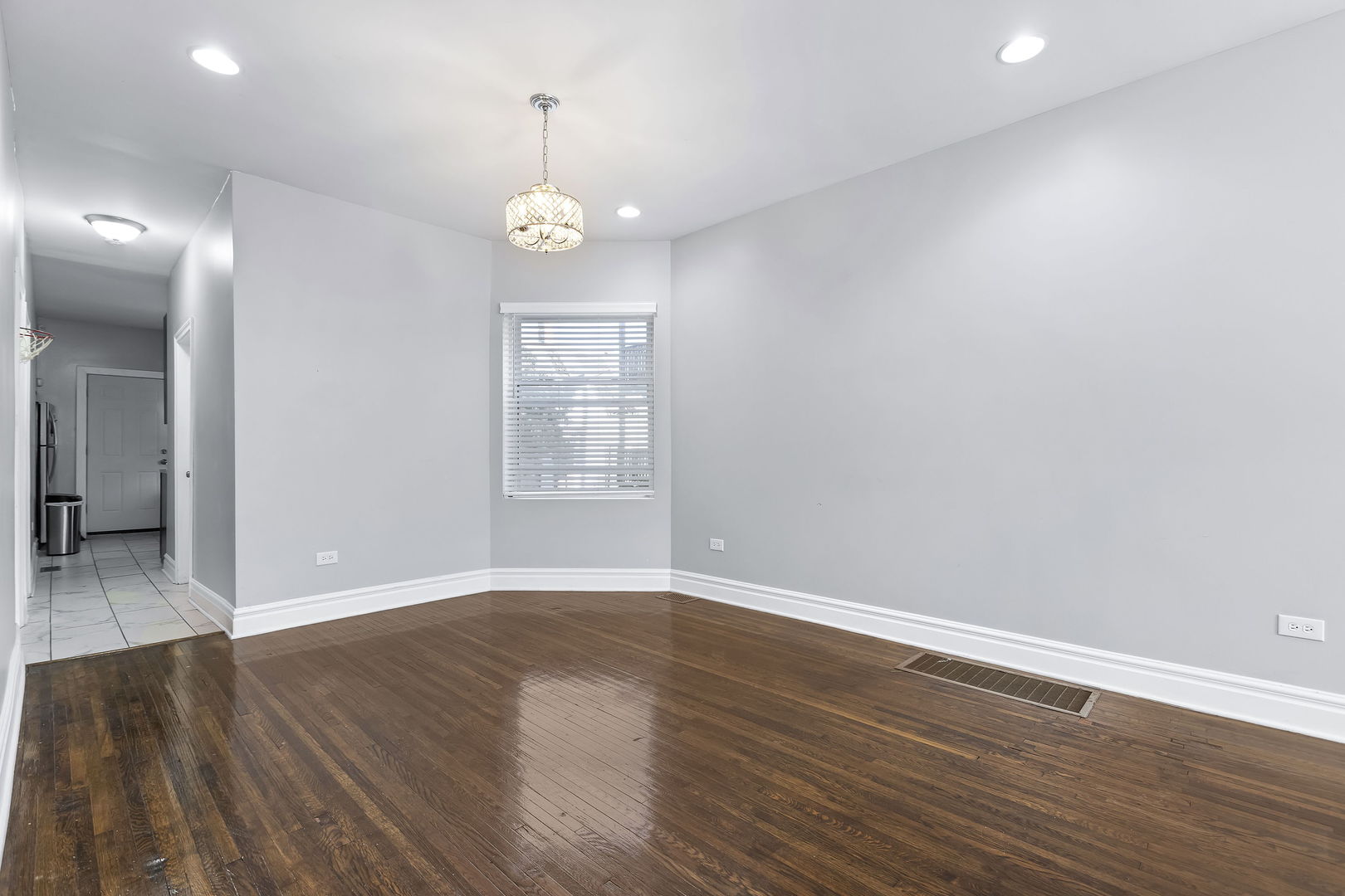 6321 South Champlain Avenue Chicago, IL 60637 - Photo 4 of 14 an empty room with wooden floor and windows