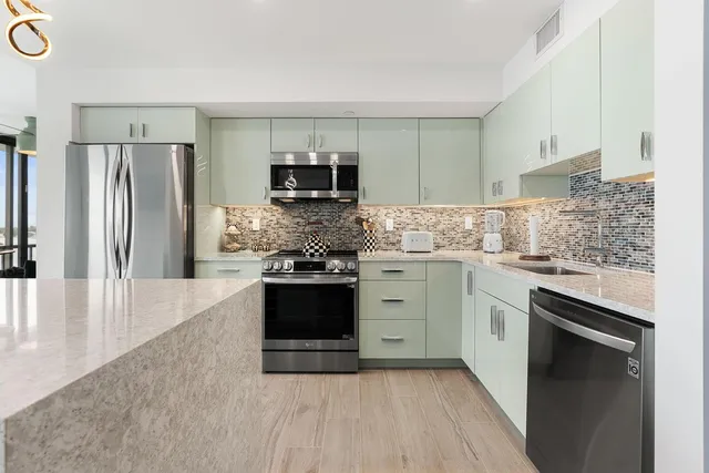 a kitchen with stainless steel appliances granite countertop a stove a sink and a refrigerator