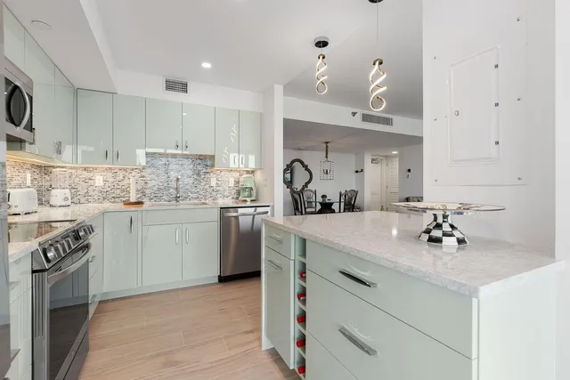 a kitchen with a sink dishwasher a stove and white cabinets with wooden floor