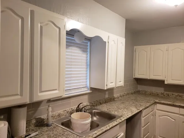 a kitchen with granite countertop a sink a stove and cabinets