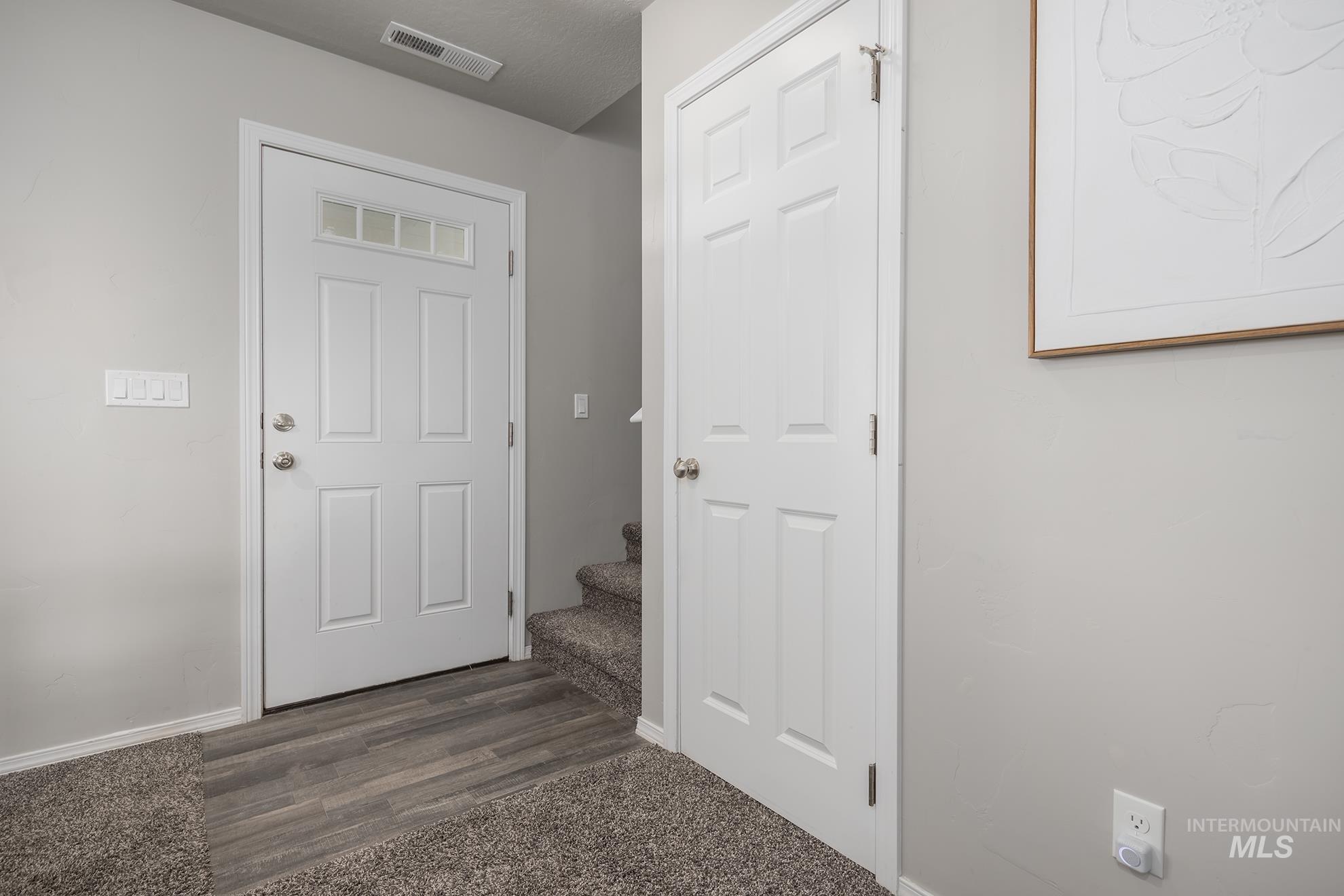 1049 Price Road Weiser, ID 83672 - Photo 19 of 47 Entryway featuring a white paneled door with glass inserts, wood-finish flooring, and a carpeted staircase