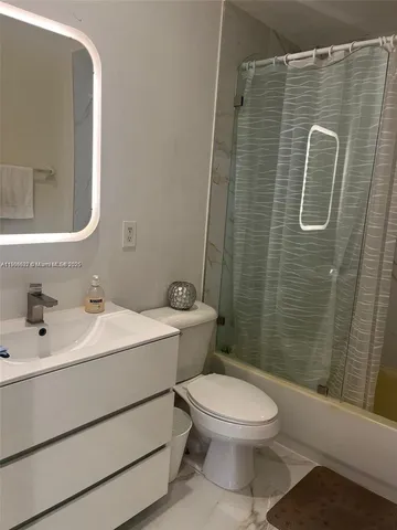 a bathroom with a white toilet sitting next to a white sink a shower and a sink