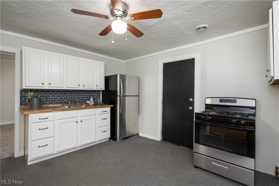 6273-6275 Manchester Road Clinton, OH 44216 - Photo 5 of 27 Kitchen featuring stainless steel refrigerator, ceiling fan, tasteful backsplash, gas range, and butcher block countertops