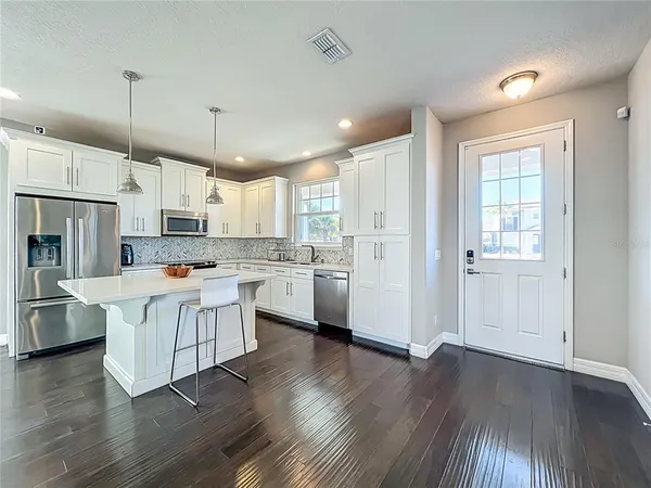 a kitchen with stainless steel appliances white cabinets a sink a stove a refrigerator and a oven