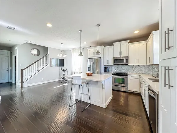 a kitchen with stainless steel appliances granite countertop white cabinets a sink a stove and a microwave