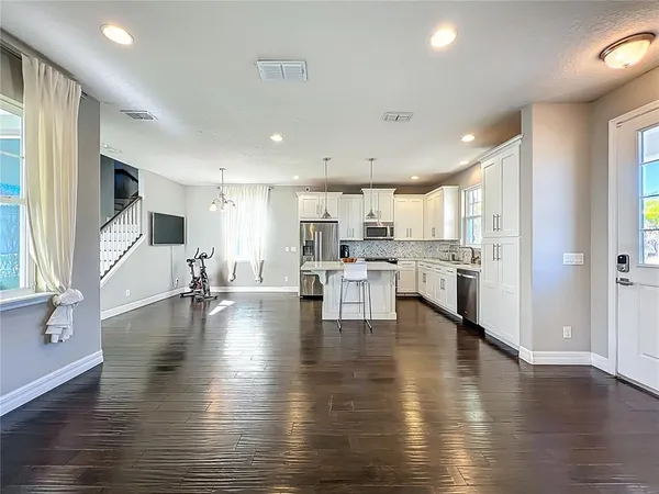 a kitchen with stainless steel appliances granite countertop a refrigerator a oven a stove and a wooden floors