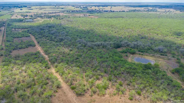 an aerial view of residential houses with outdoor space and trees