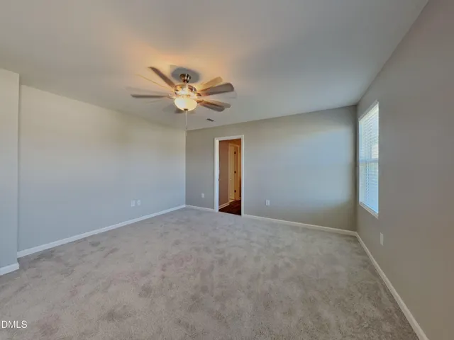 an empty room with a window and a fan