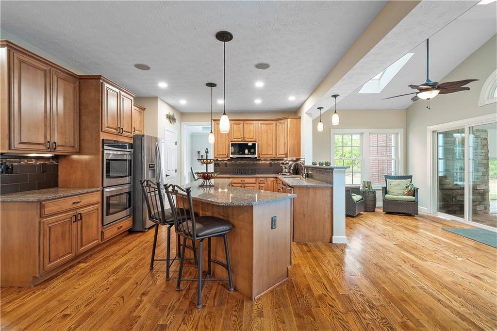 192 Baldwin Road Carnegie, PA 15106 - Photo 13 of 50 a kitchen with stainless steel appliances kitchen island granite countertop a stove a refrigerator a oven a sink with island and chairs with wooden floor