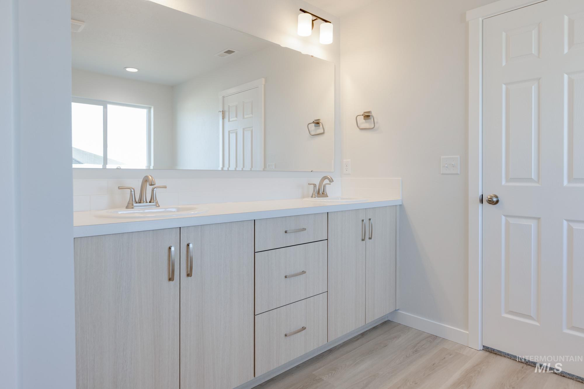 1639 Celina Street Middleton, ID 83644 - Photo 15 of 19 Dual vanity with light wood-finish cabinetry, brushed nickel hardware, and white countertops