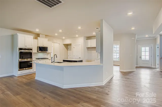 a view of kitchen with cabinets stainless steel appliances and wooden floor