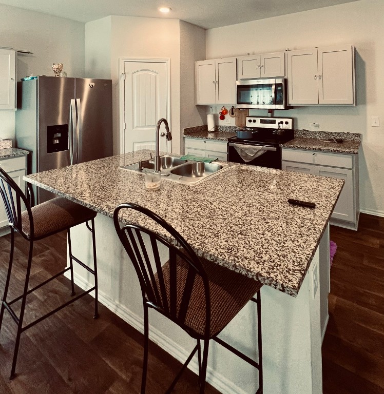 13120 Roving Pass Elgin, TX 78621 - Photo 3 of 21 a kitchen with stainless steel appliances granite countertop a table chairs microwave and refrigerator