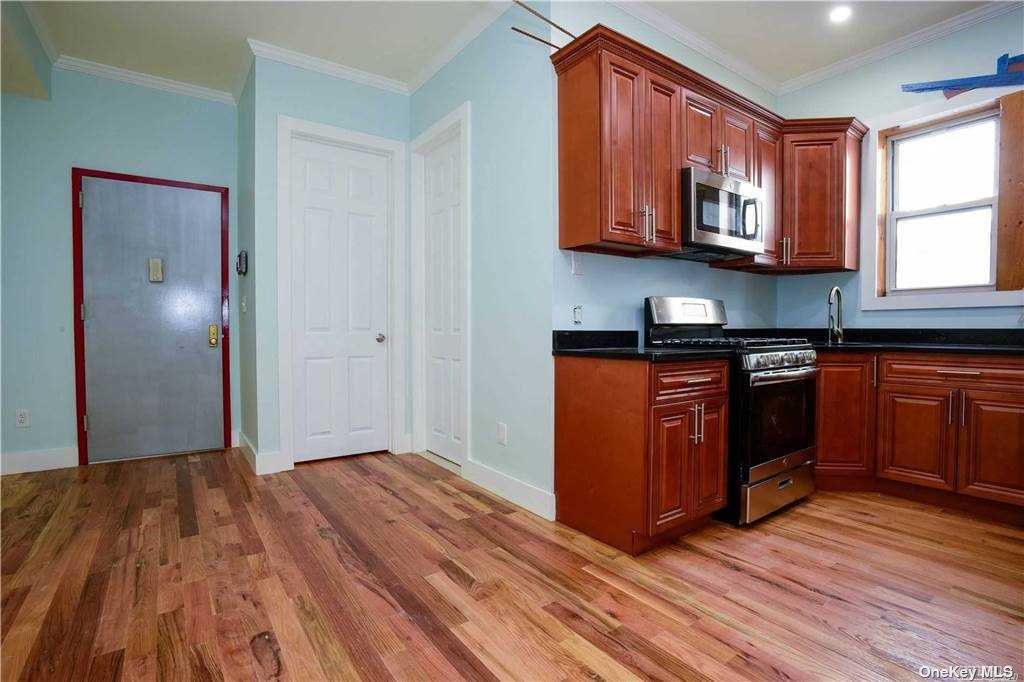 a kitchen with stainless steel appliances granite countertop a stove a sink and a microwave oven with wooden floor
