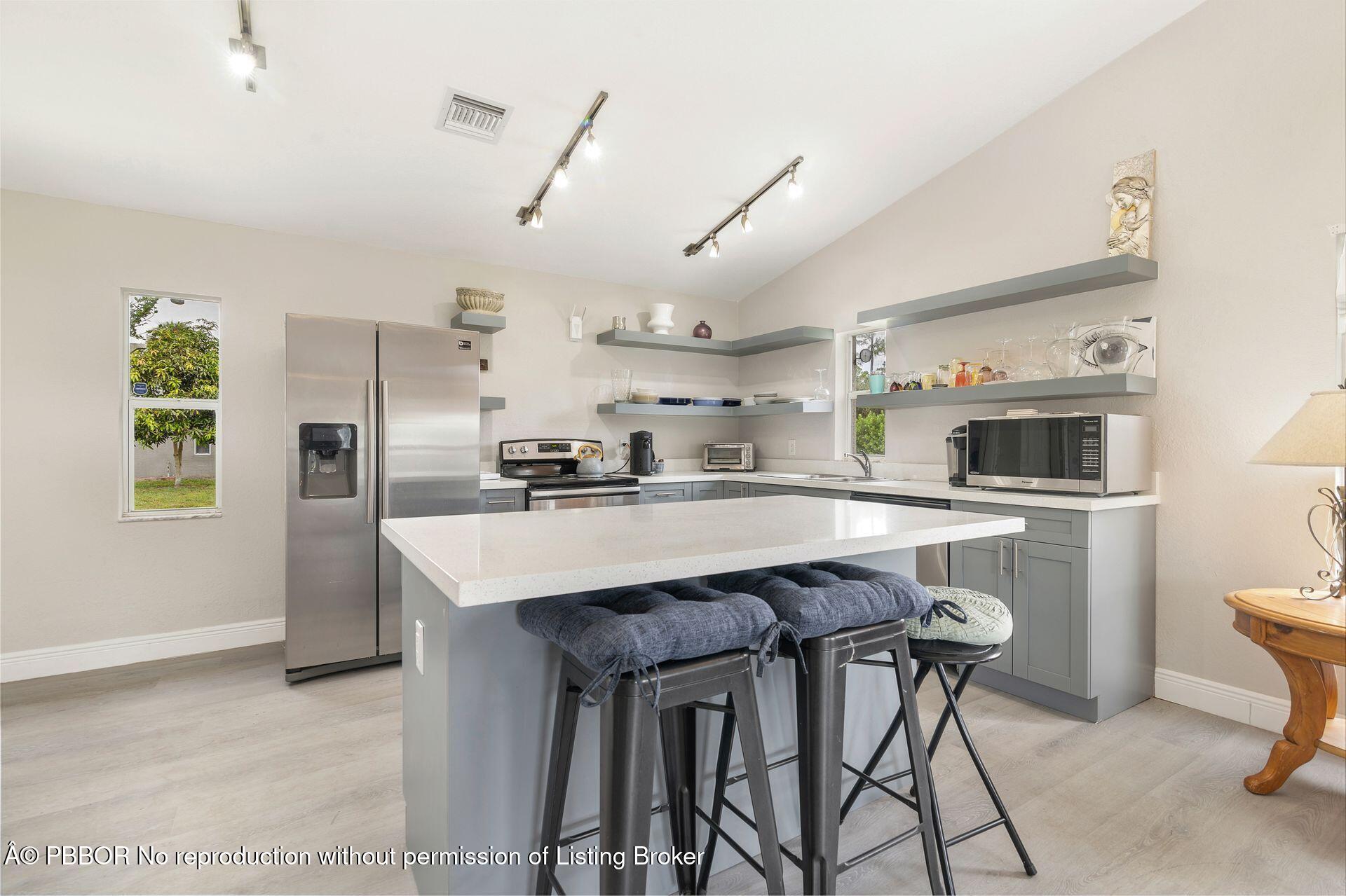2770 E Road Loxahatchee, FL 33470 - Photo 22 of 51 a kitchen with kitchen island a refrigerator stove and microwave