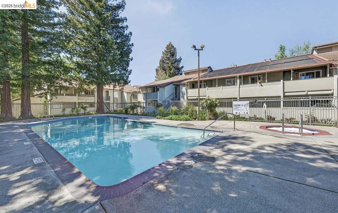 1505 Kirker Pass Road, Unit 214 Concord, CA 94521 - Photo 48 of 55 Community swimming pool with an integrated spa, surrounded by a concrete deck and metal fencing
