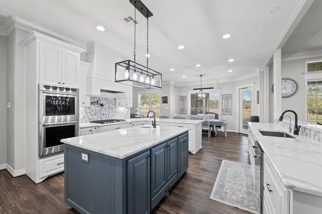 a large kitchen with stainless steel appliances granite countertop a stove and a sink